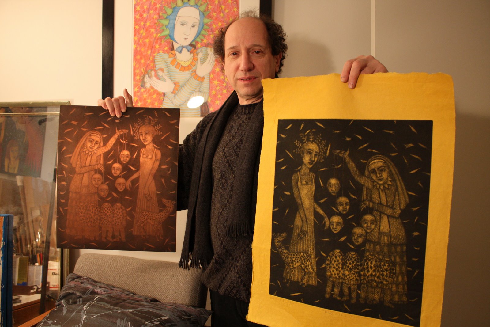 Bert Menco holding two prints, surrounded by his artwork